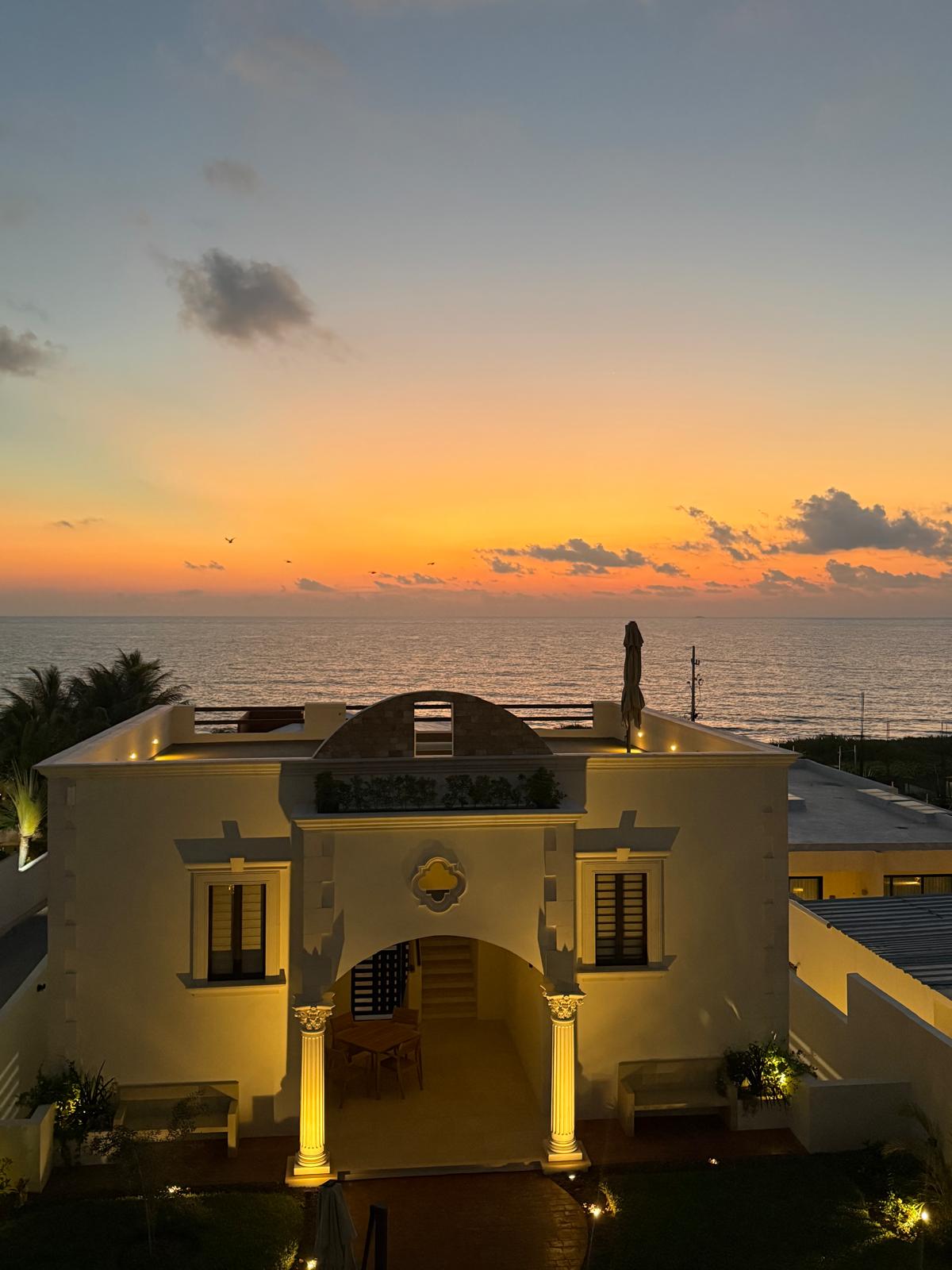 Estate facade glowing at sunrise above the Caribbean
