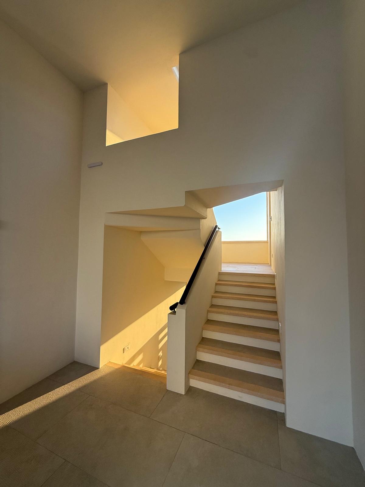 Sunlit stairwell rising to the rooftop terrace