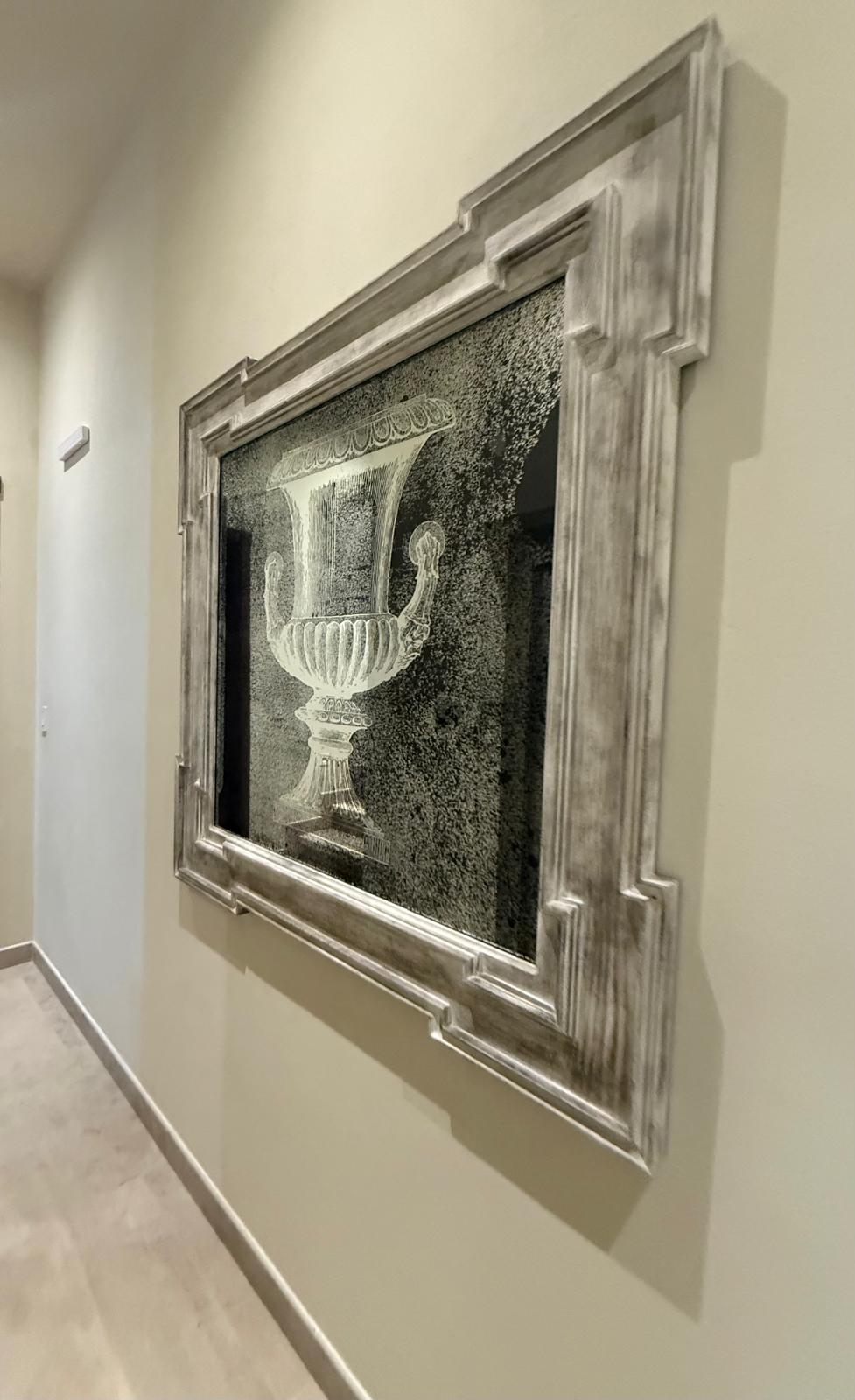 Framed classical urn engraving in a distressed whitewashed wood frame, hanging in a hallway
