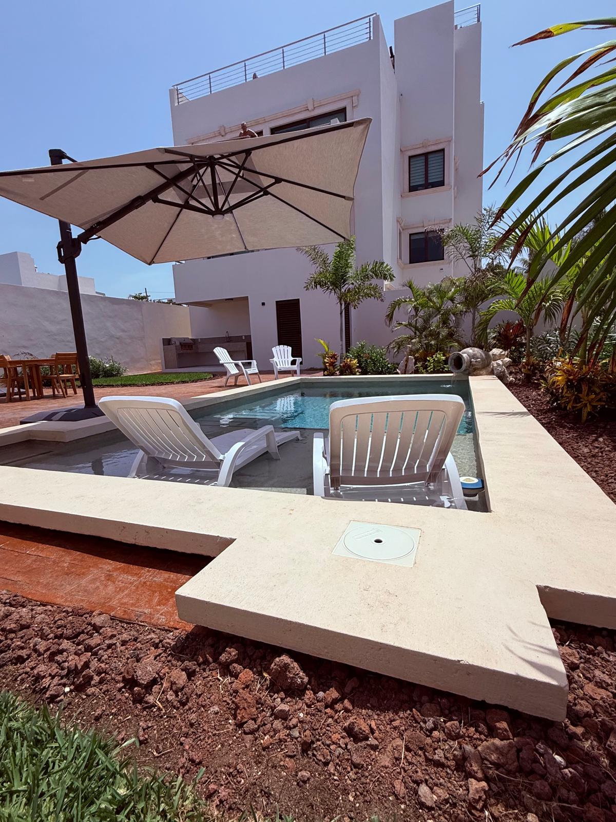 Poolside loungers and cantilever umbrella beside the estate building