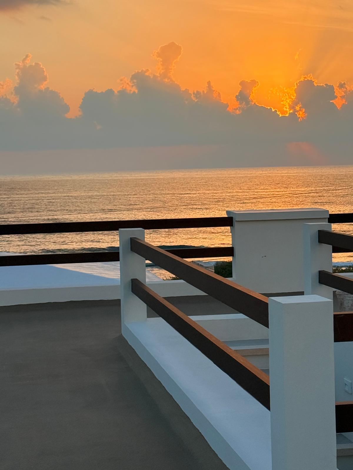Golden sunrise light on the sea beyond the rooftop railing