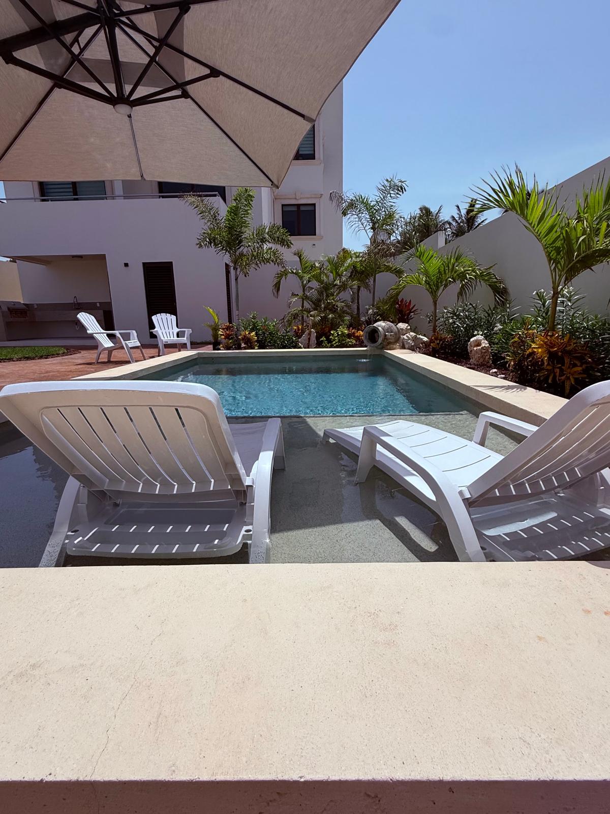 Courtyard pool with in-water loungers under a shade umbrella
