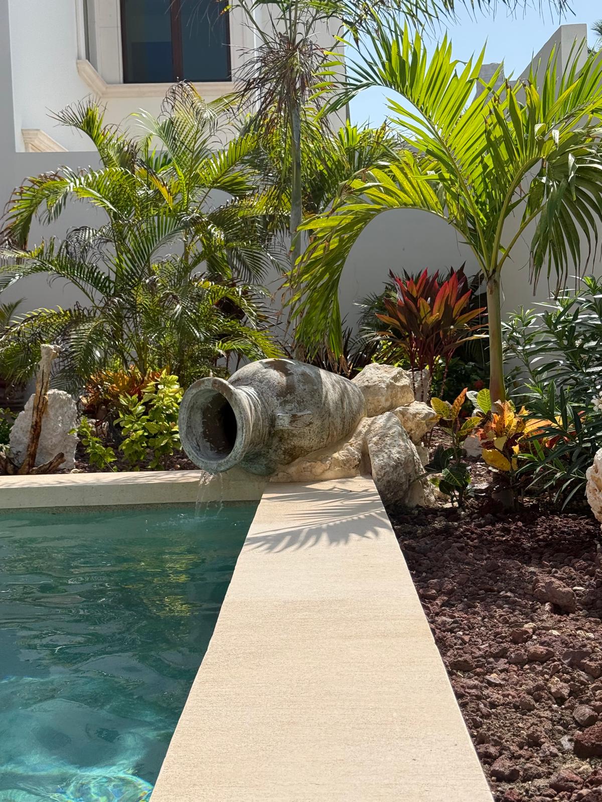 Stone amphora fountain spilling into the courtyard pool