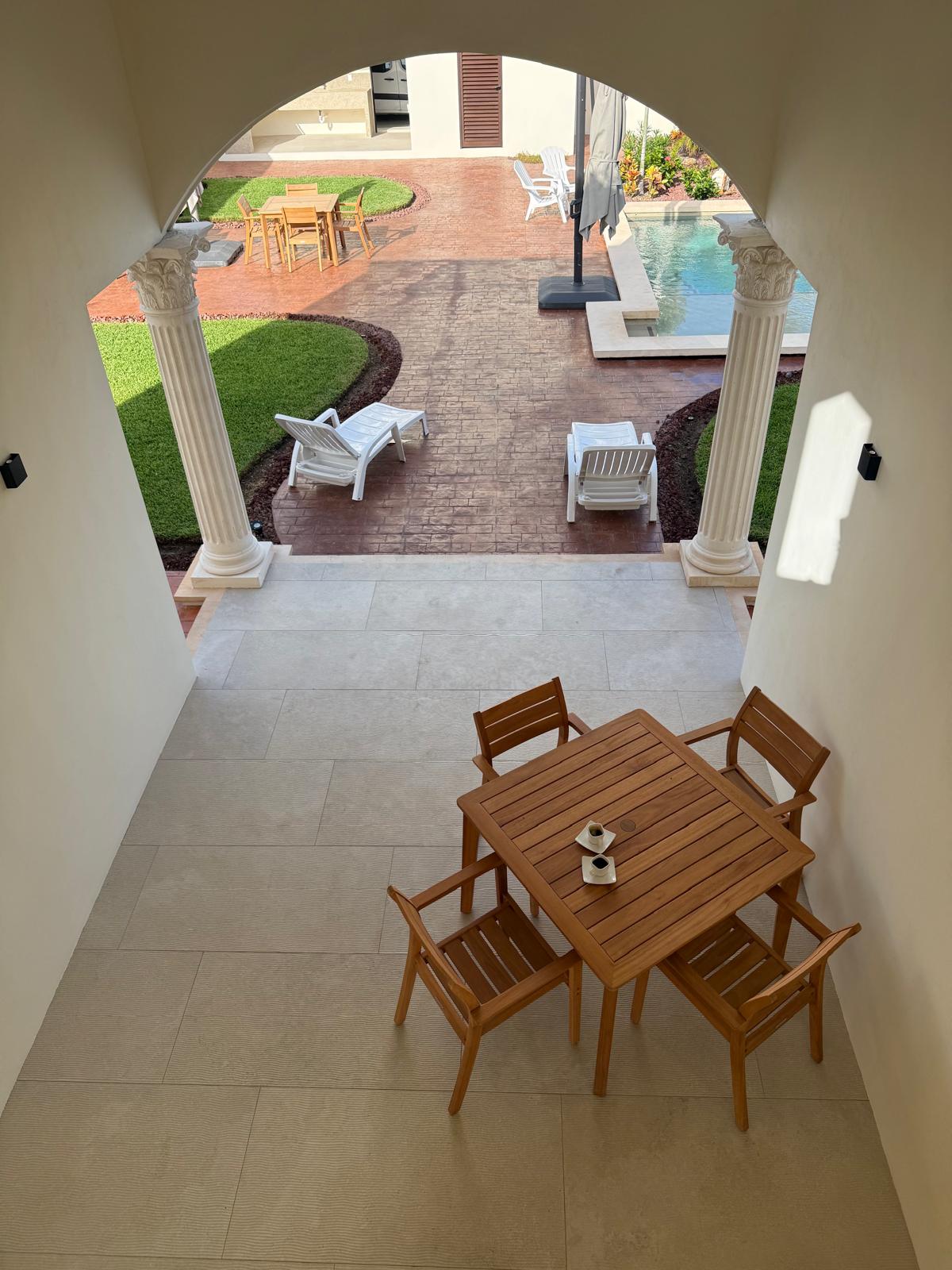 Archway view from the loggia to the courtyard pool and teak dining table