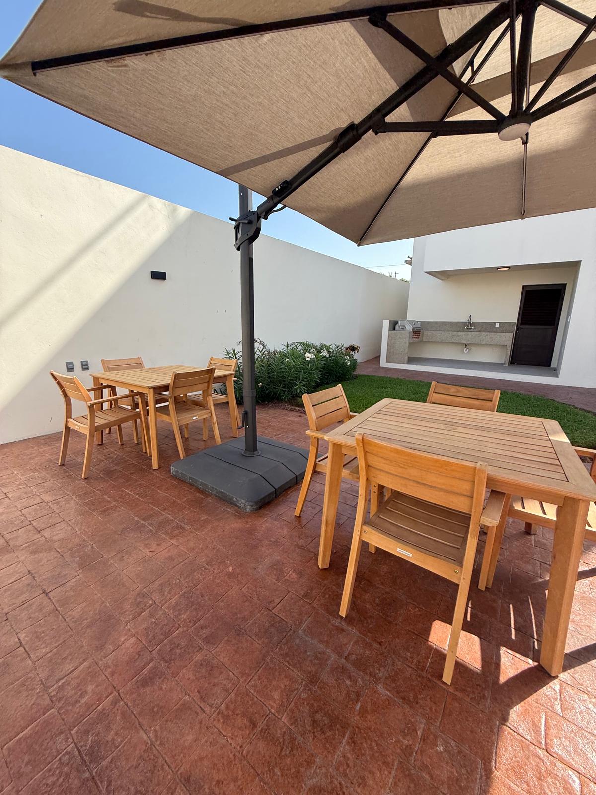 Teak dining tables under the large courtyard umbrella