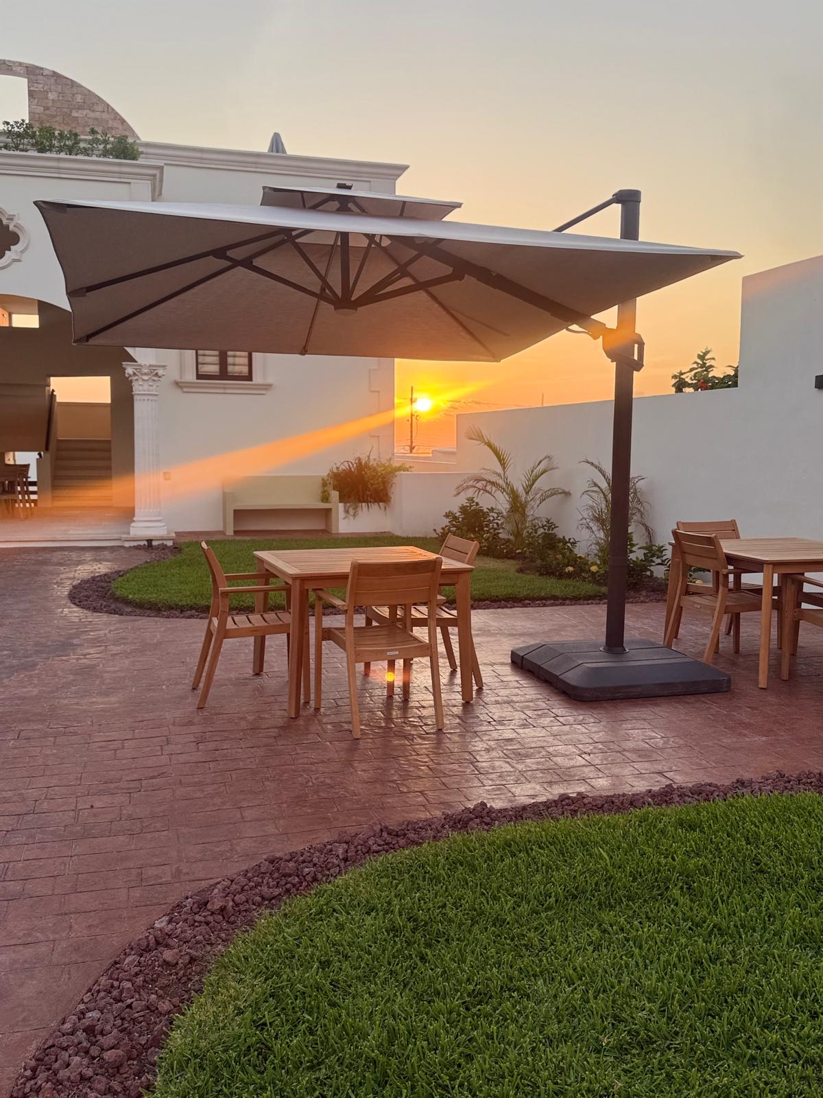 Courtyard teak dining tables under the cantilever umbrella at sunset