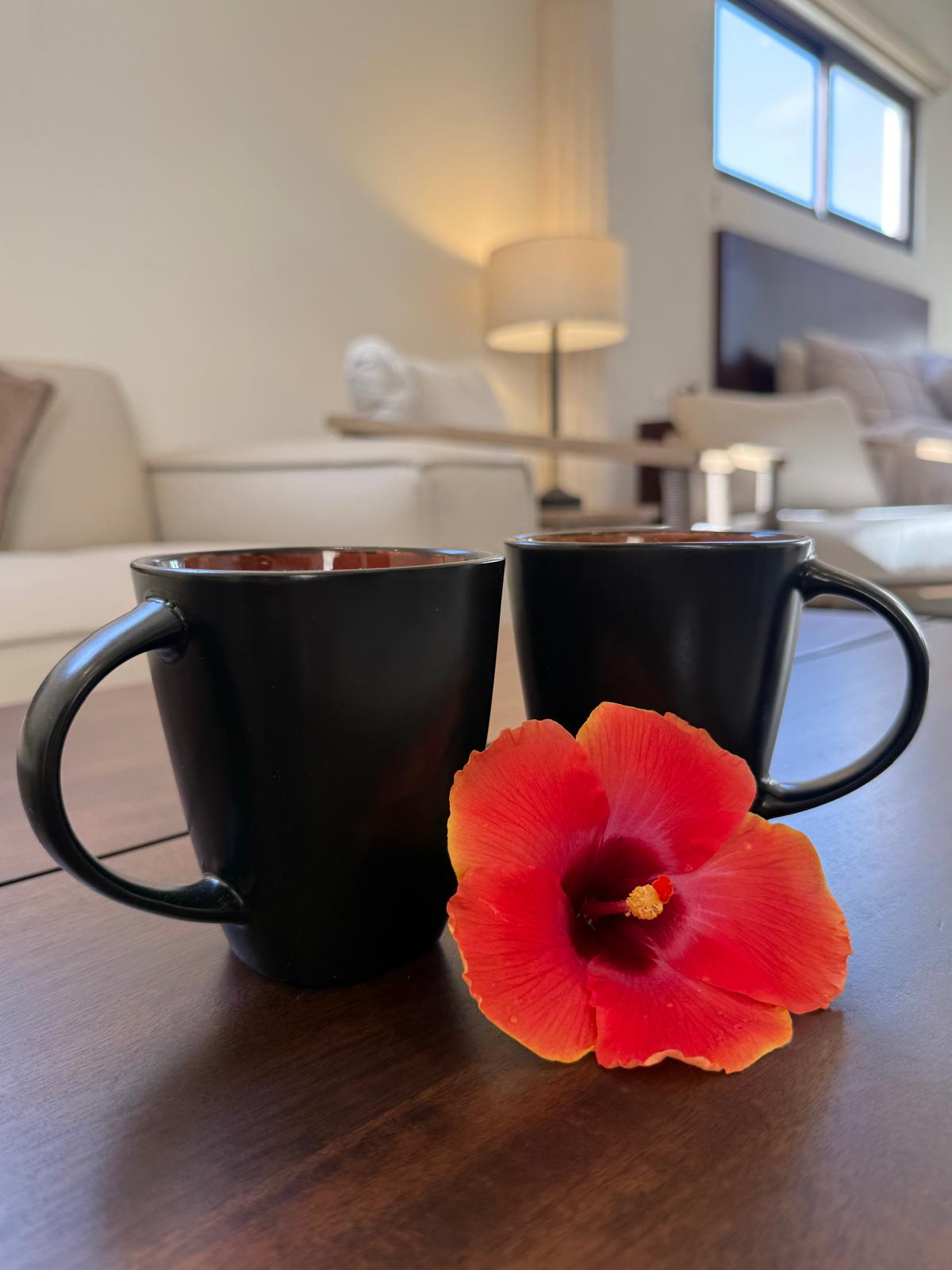 Two coffee mugs and a hibiscus flower in a suite living room