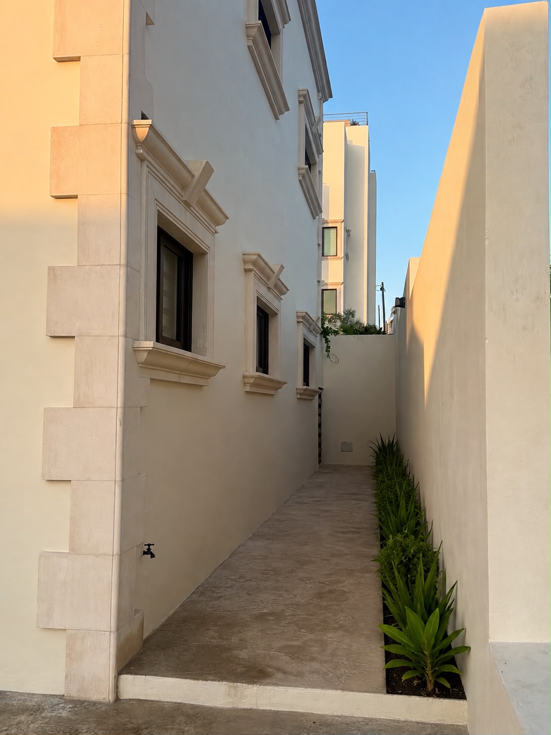 Stone-trimmed facade along a garden walkway at golden hour