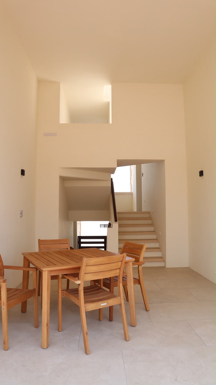 Double-height entry hall with teak dining table and stairs