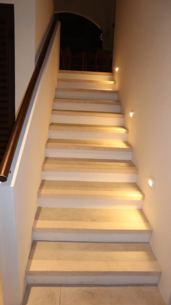 Lit stone staircase with wood handrail