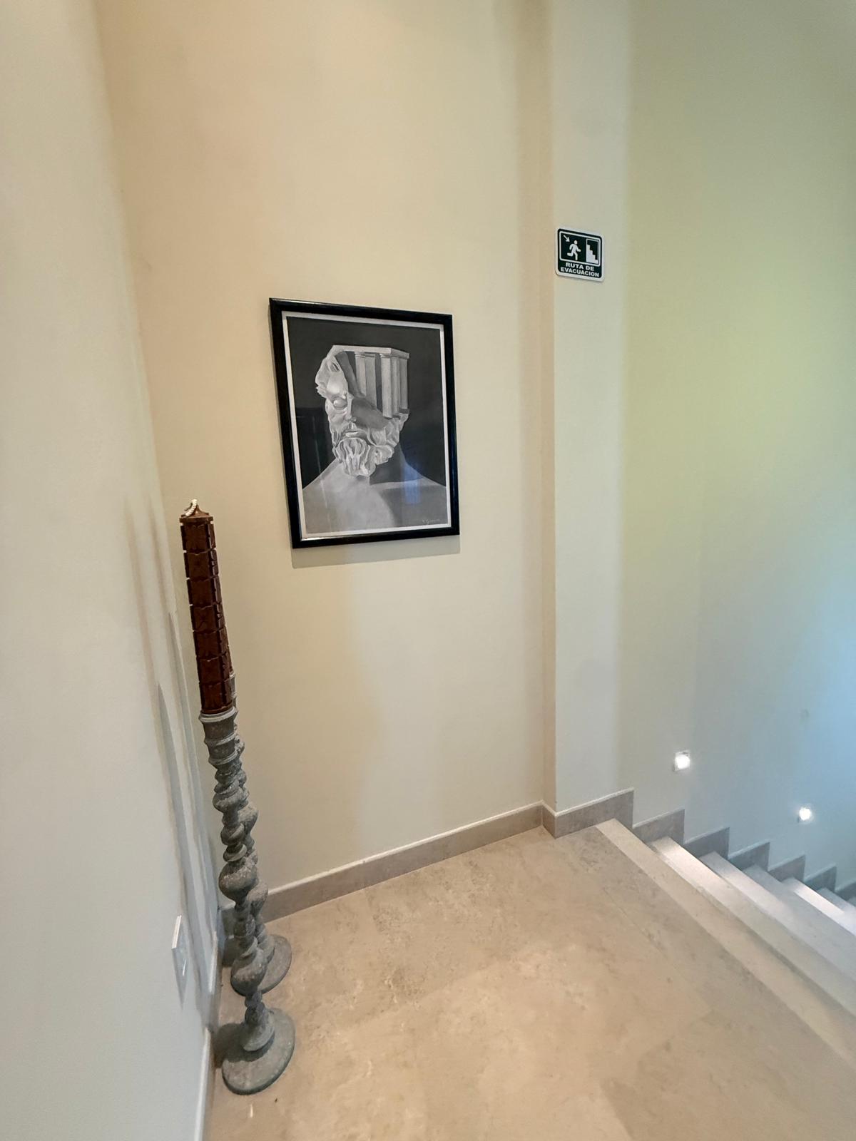Stairwell landing with framed charcoal artwork and a carved candle stand