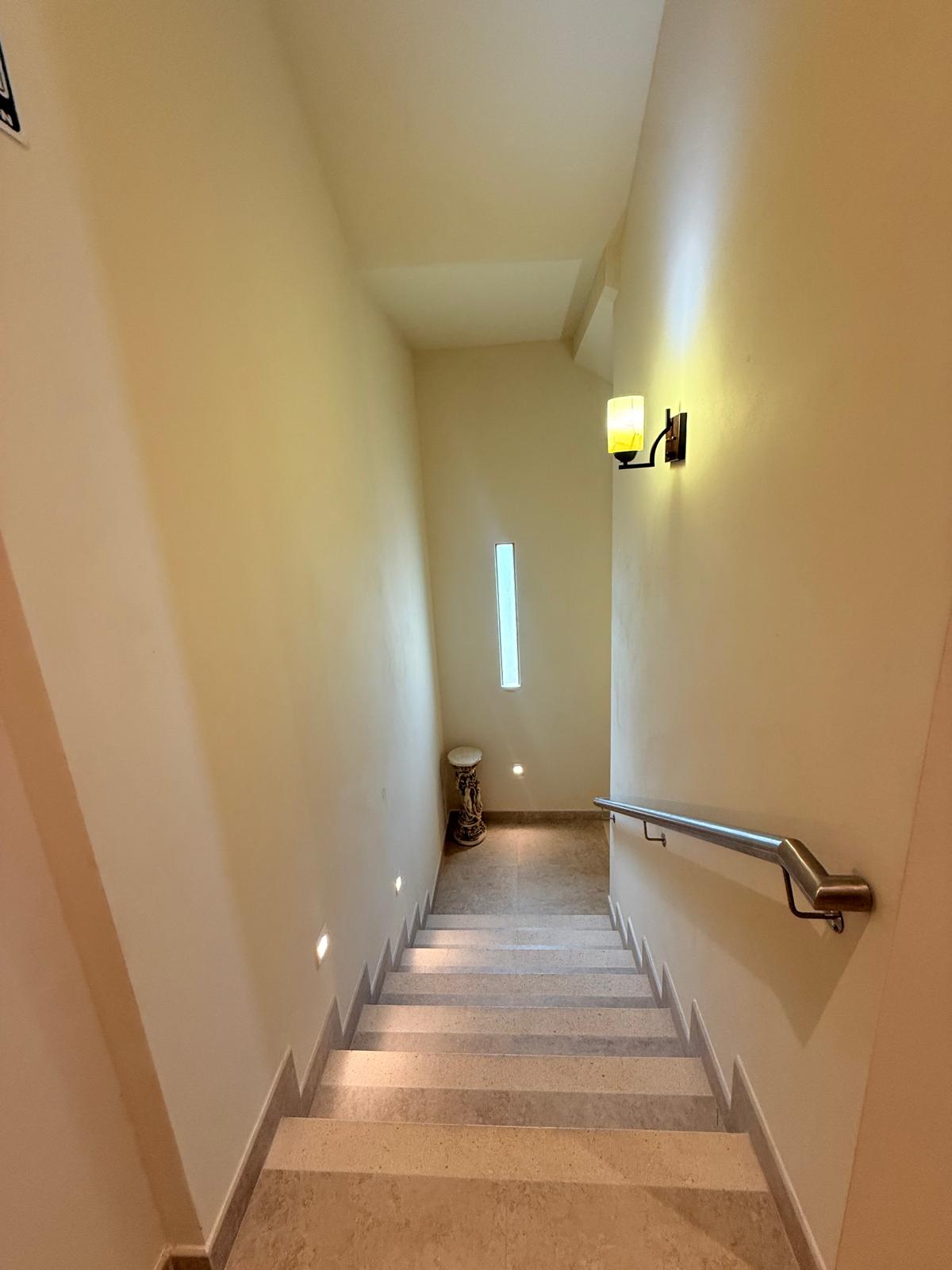Travertine stairway with a wall sconce and slim window