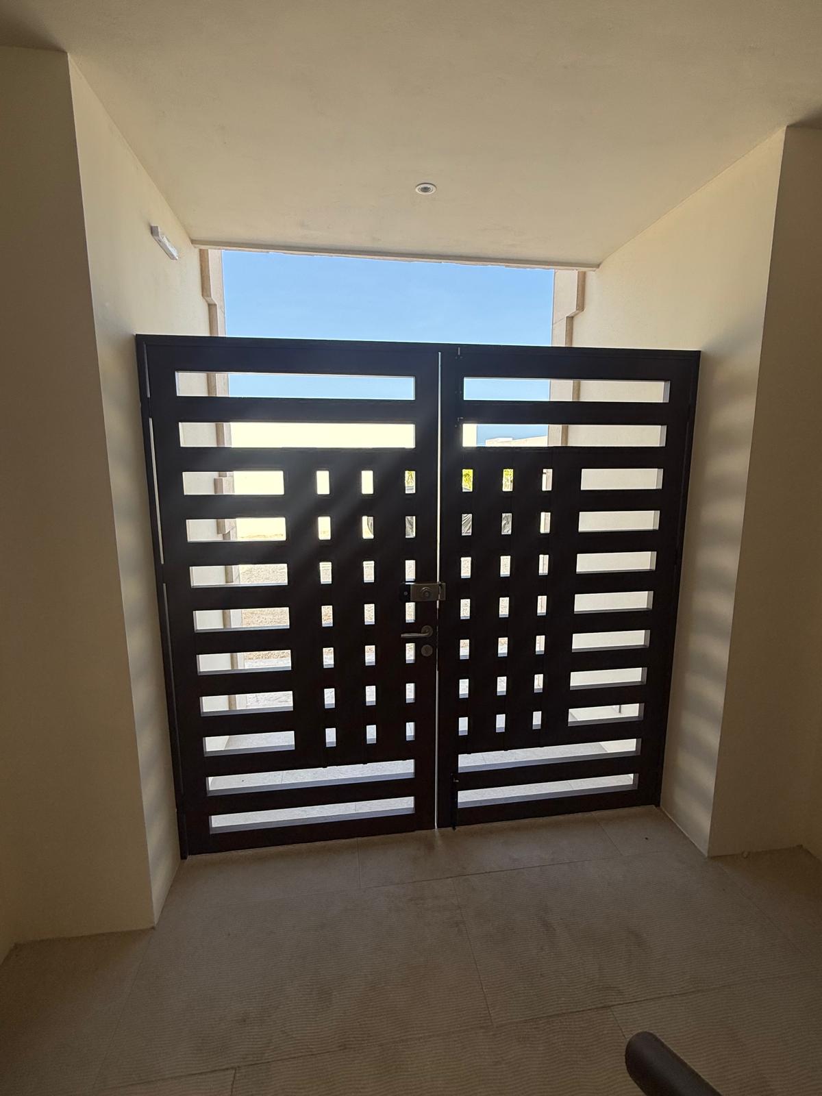 Dark slatted double entry doors opening to the sunlit grounds