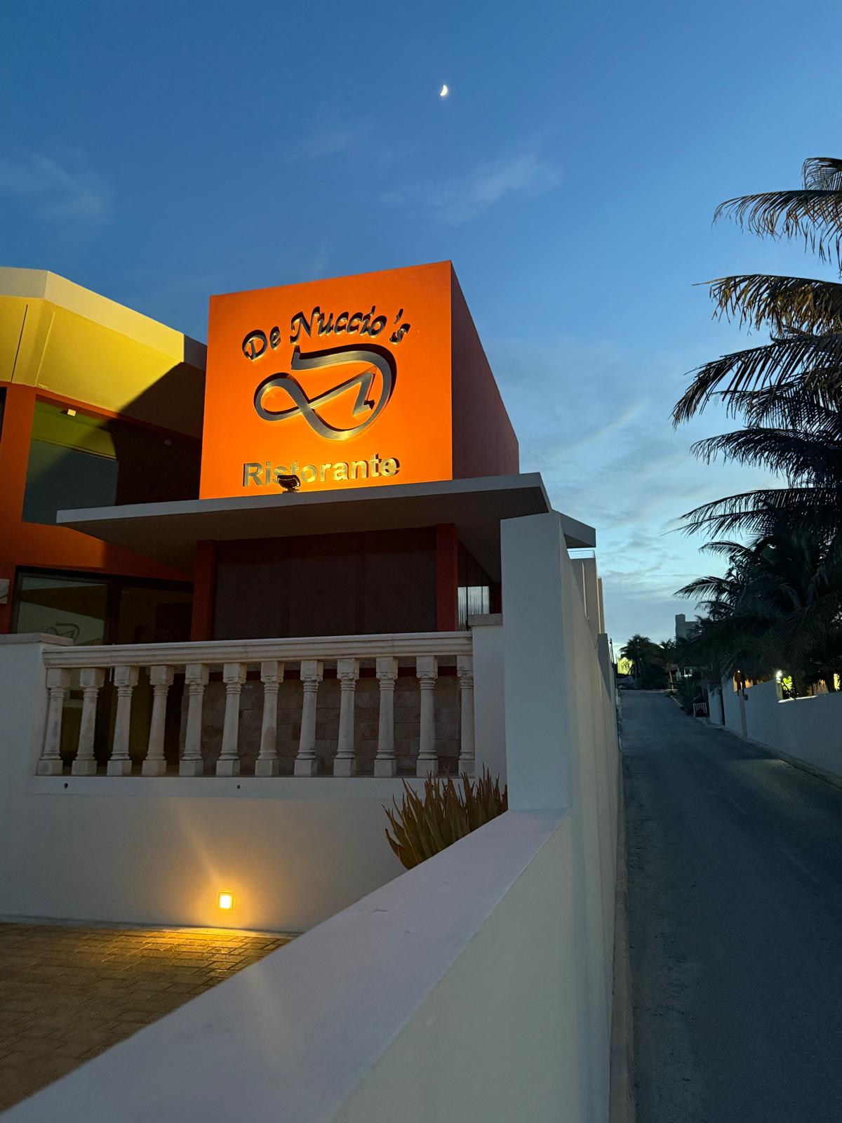 DeNuccio's Ristorante illuminated orange sign at blue hour with a crescent moon