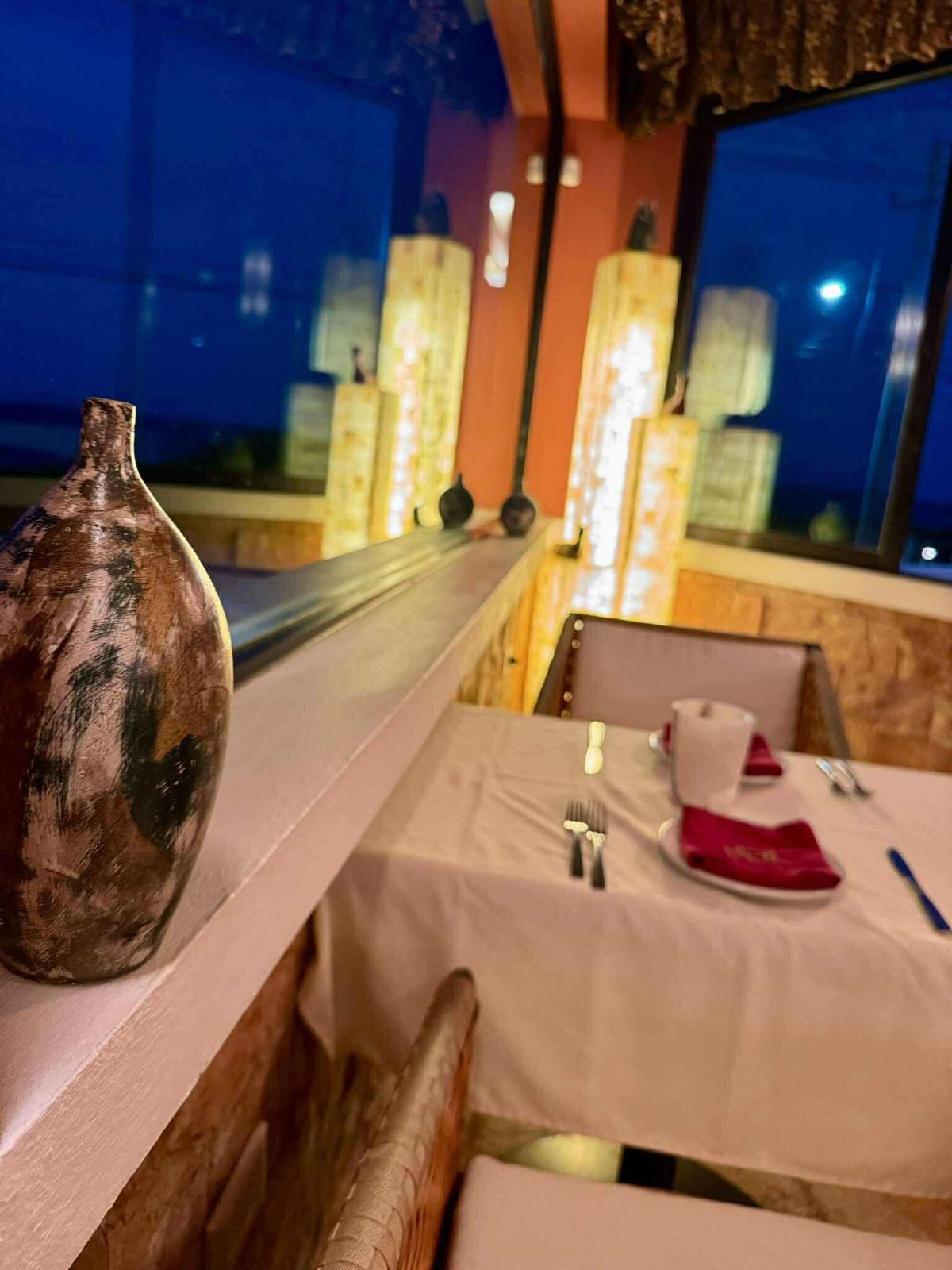 Evening table setting beside onyx lamps and dark blue windows