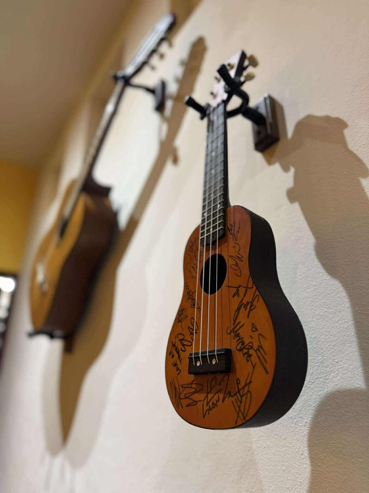 Signed ukulele and guitars displayed on the wall