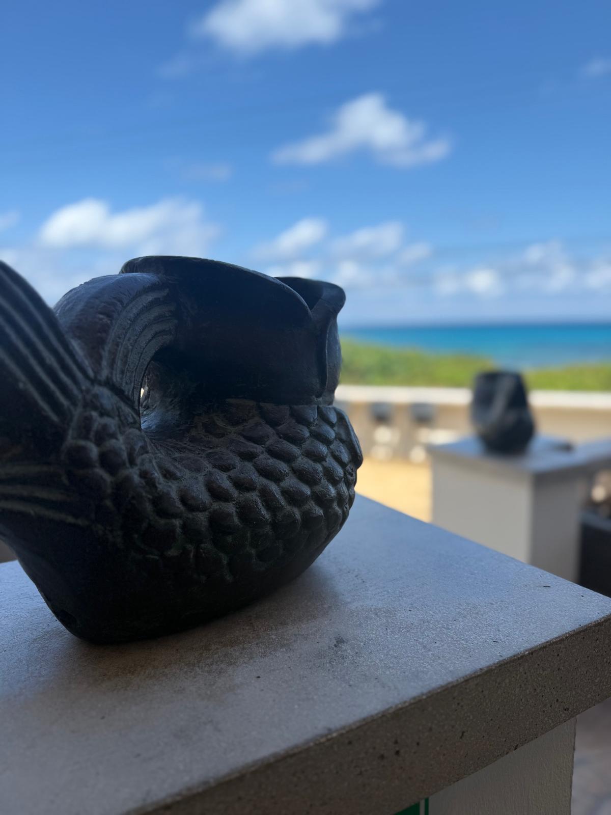 Carved stone fish sculpture overlooking the Caribbean