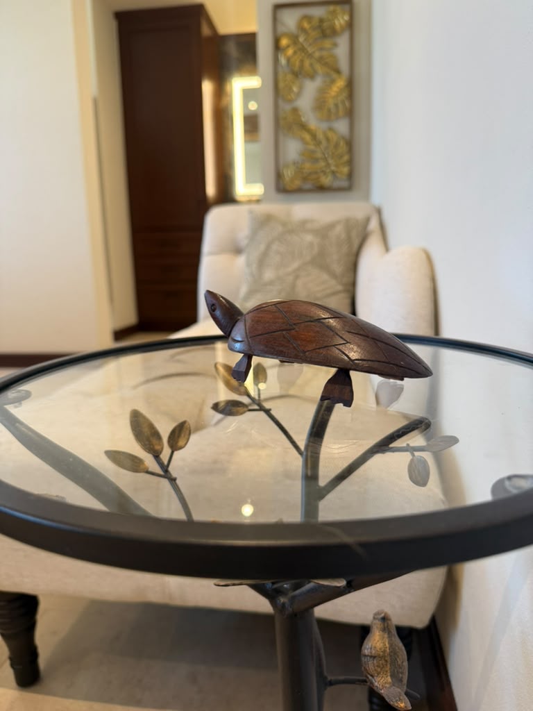 Hand-carved wooden turtle on glass side table